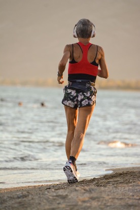 Active woman running on the beach representing healthy midlife fitness